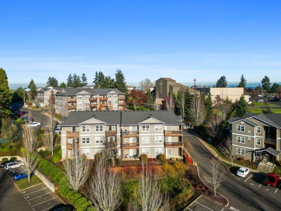 Apartment buildings and trees on a sunny hillside neighborhood under a clear blue sky