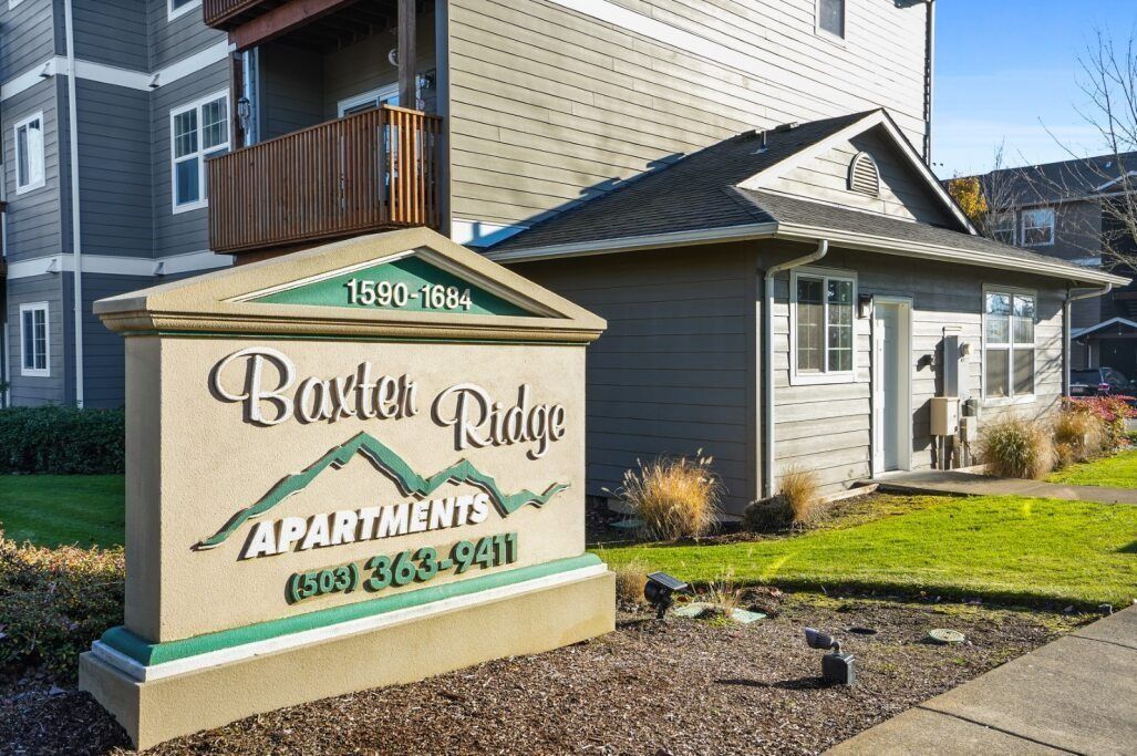 Apartment leasing sign for Brook Ridge outside a gray apartment building on a sunny day