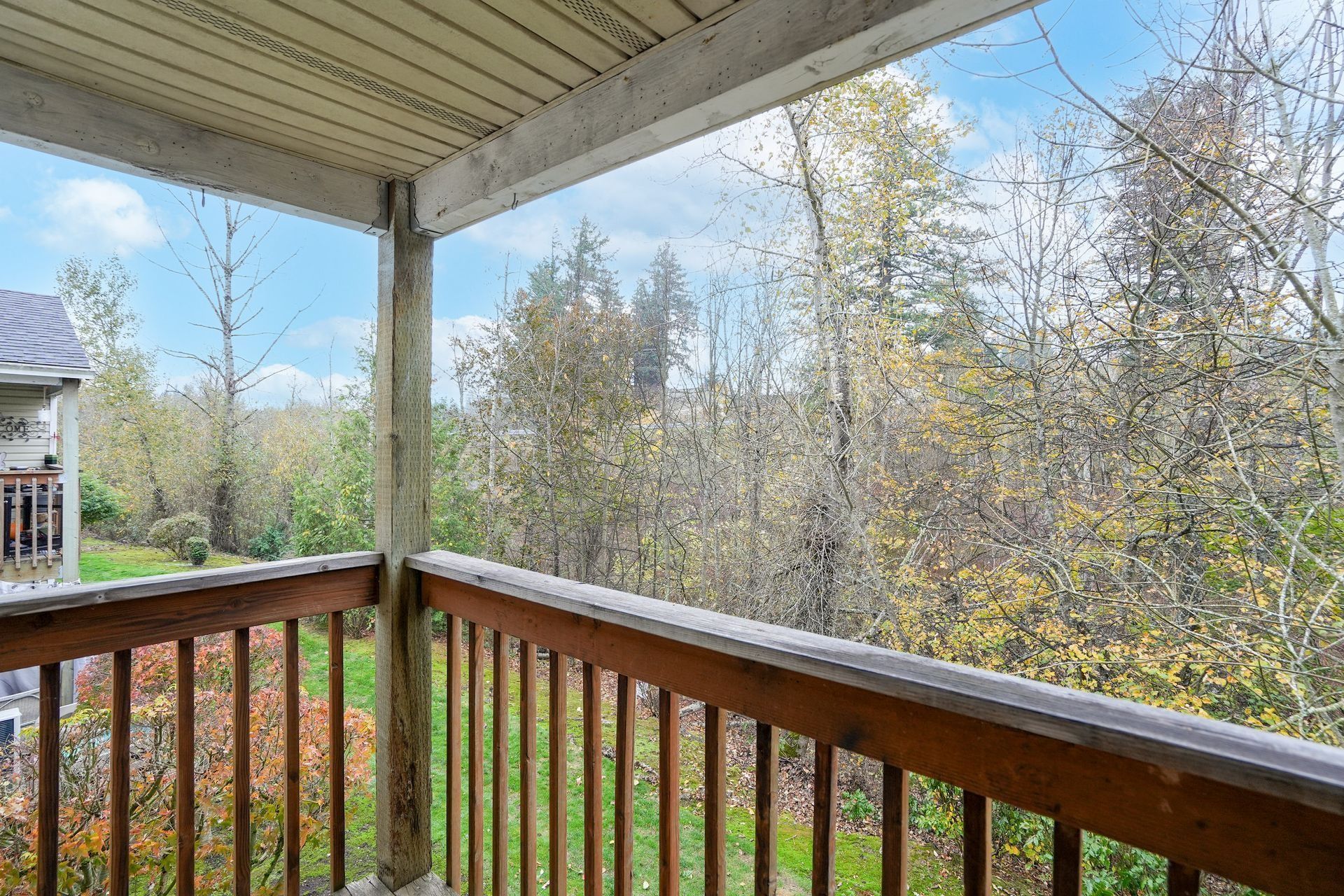 Porch with wooden railing overlooking spring trees and neighboring houses