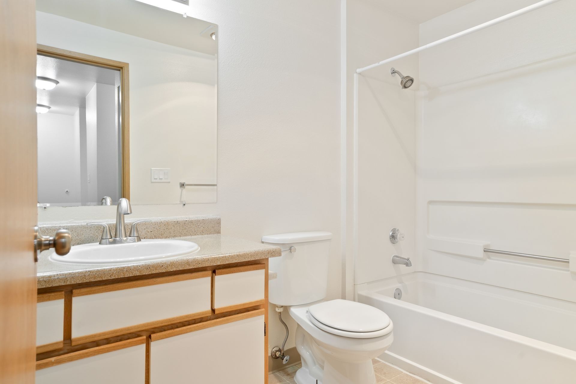 Bright bathroom with a vanity, mirror, toilet, and white bathtub with shower curtain.
