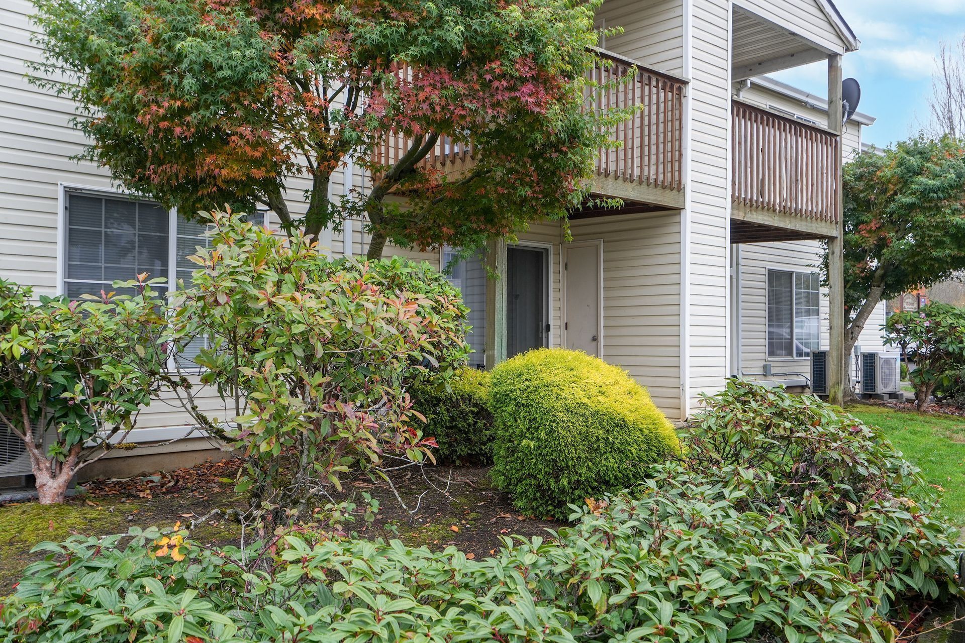 Apartment building with balconies and lush green shrubs in a landscaped courtyard