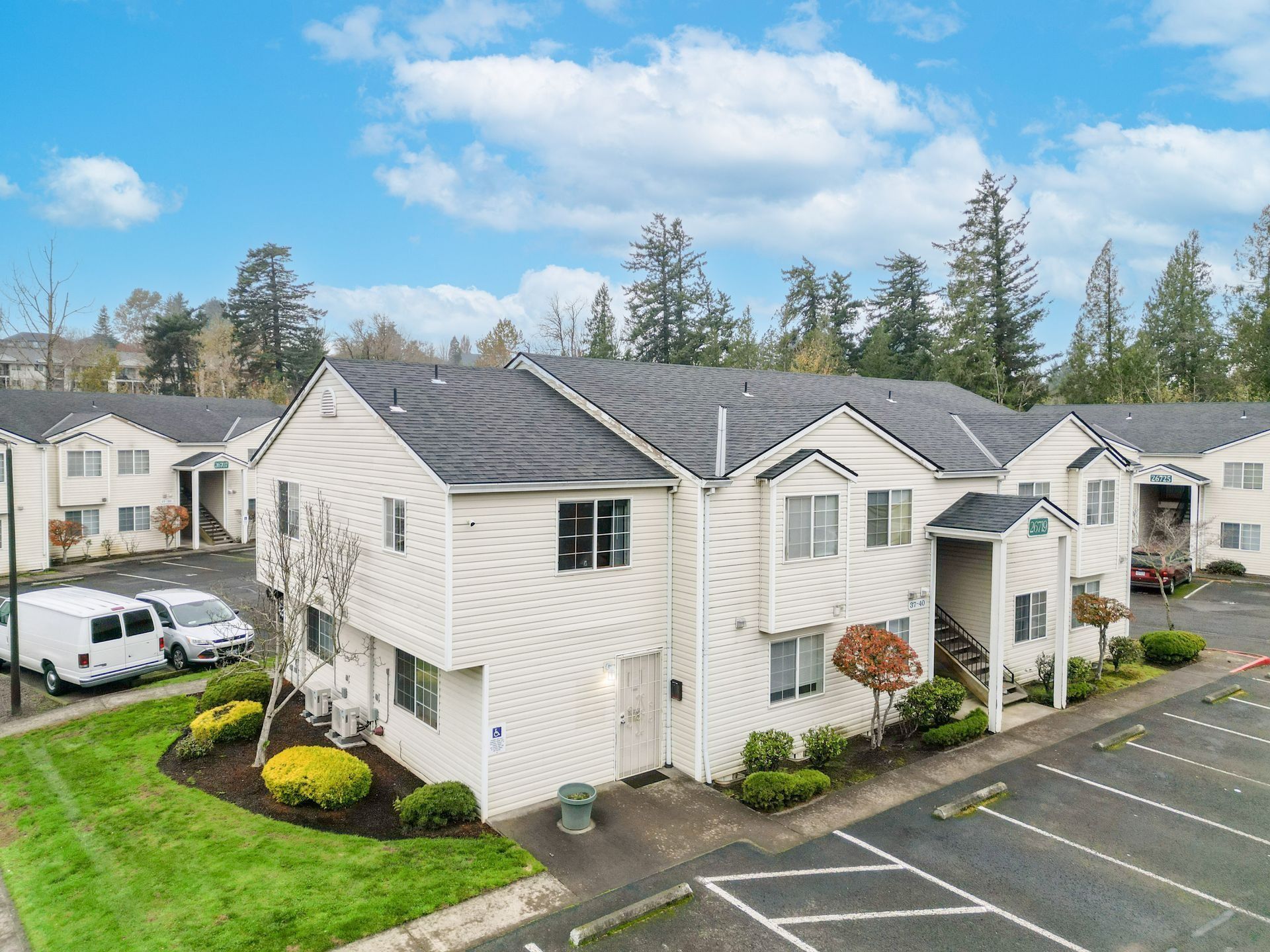 Apartment buildings with white siding and parking lot under a blue sky