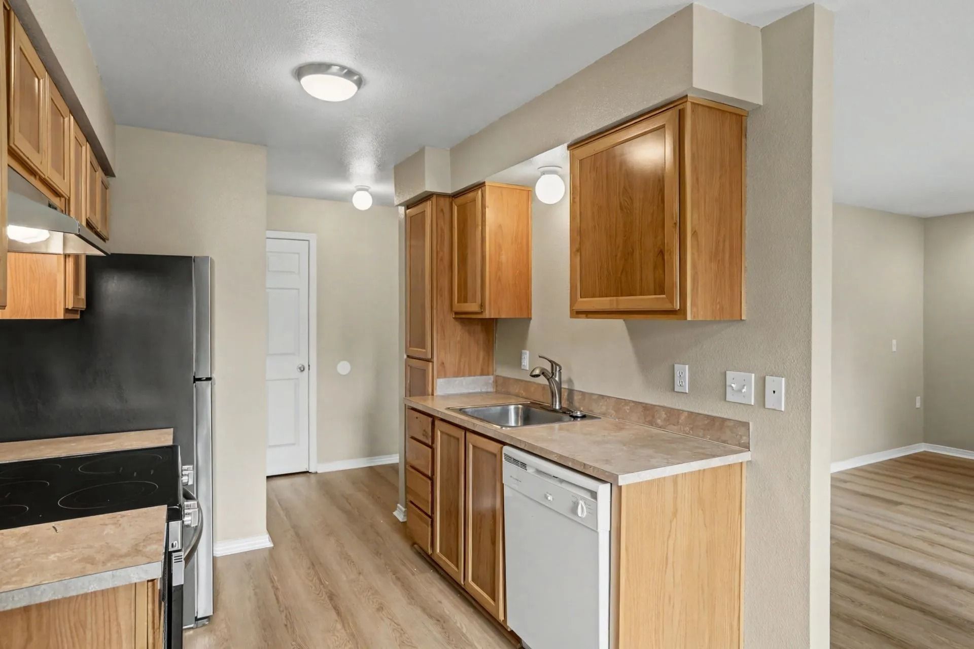 Small kitchen with wood cabinets, black appliances, white walls, and light wood flooring.