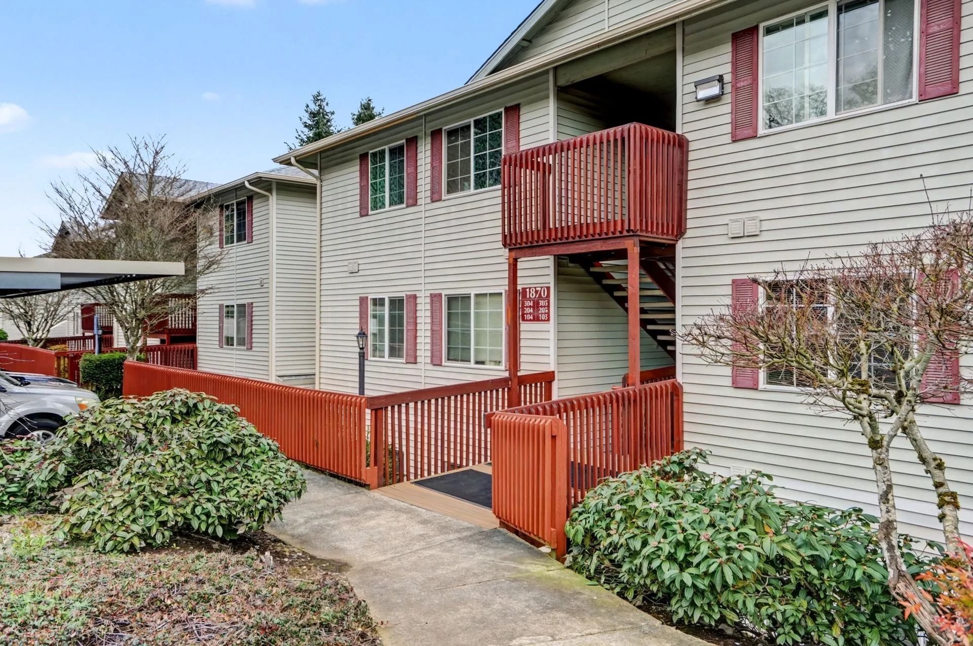 Apartment building with red balconies and fencing along a concrete walkway