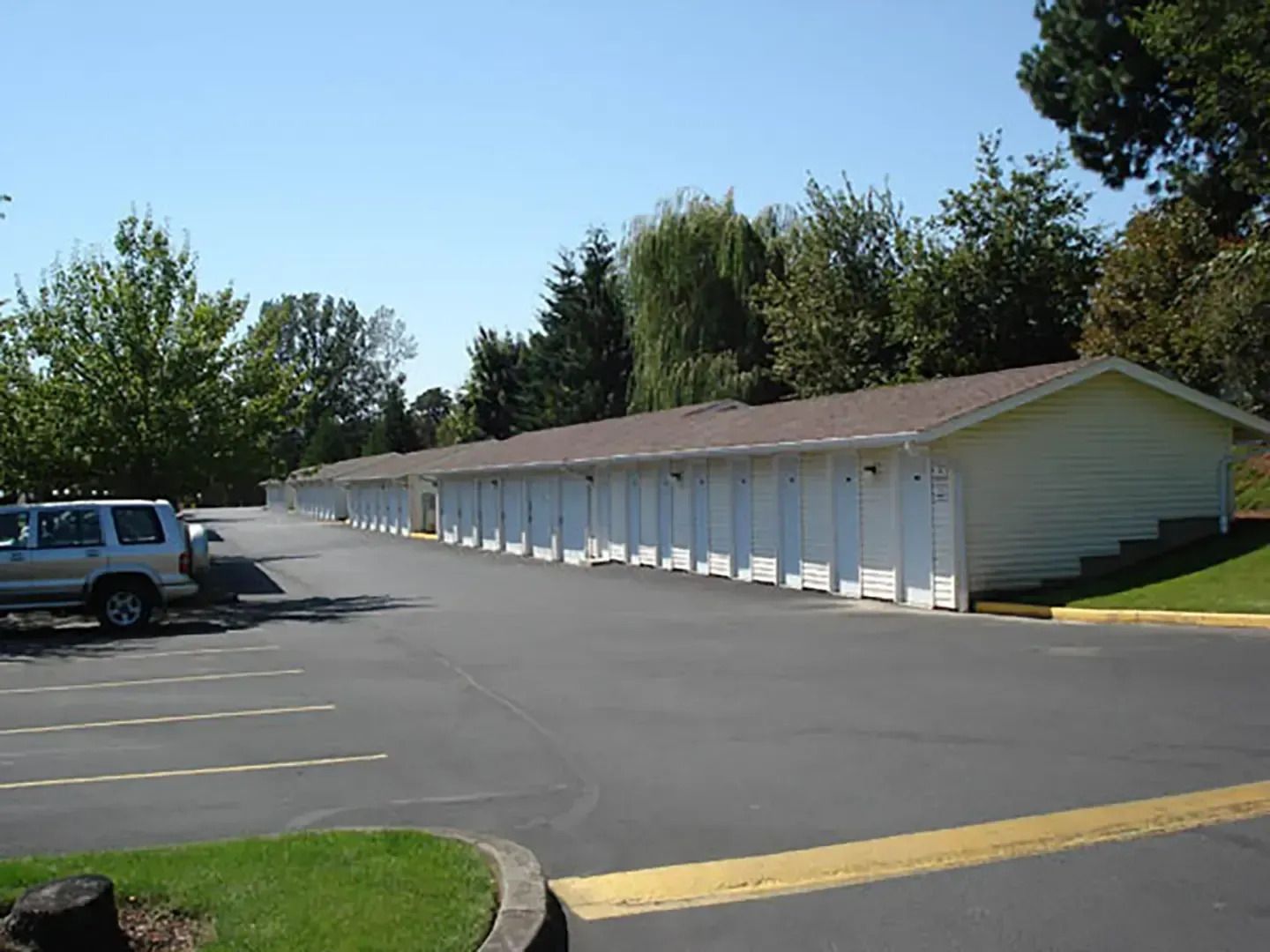 Long white motel-style building beside an empty parking lot on a sunny day