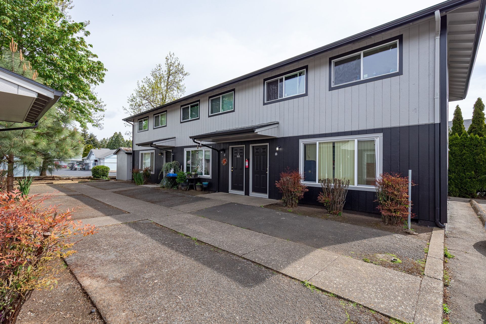 Row of dark gray townhouses with front doors and a driveway in a residential area
