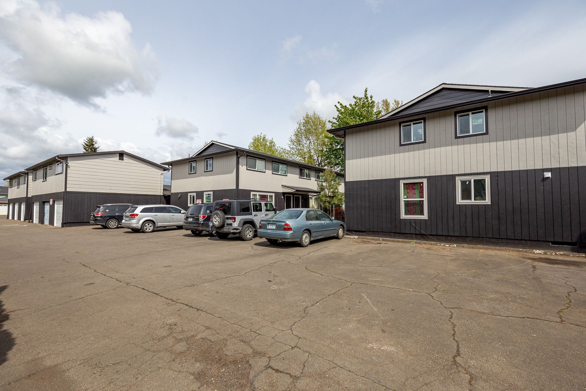 Parking lot beside low apartment buildings under a cloudy sky