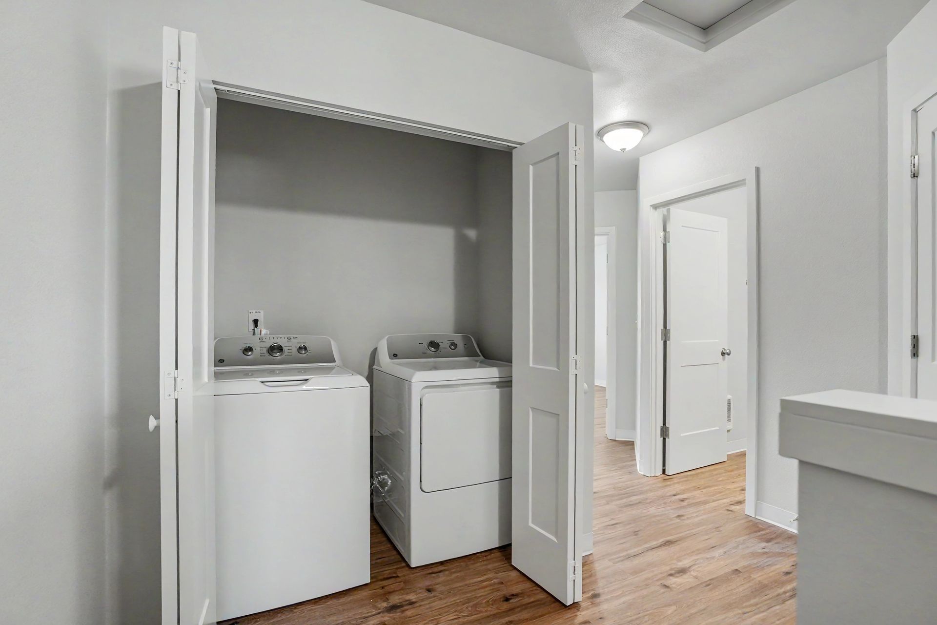 Laundry closet with a washer and dryer in a white hallway