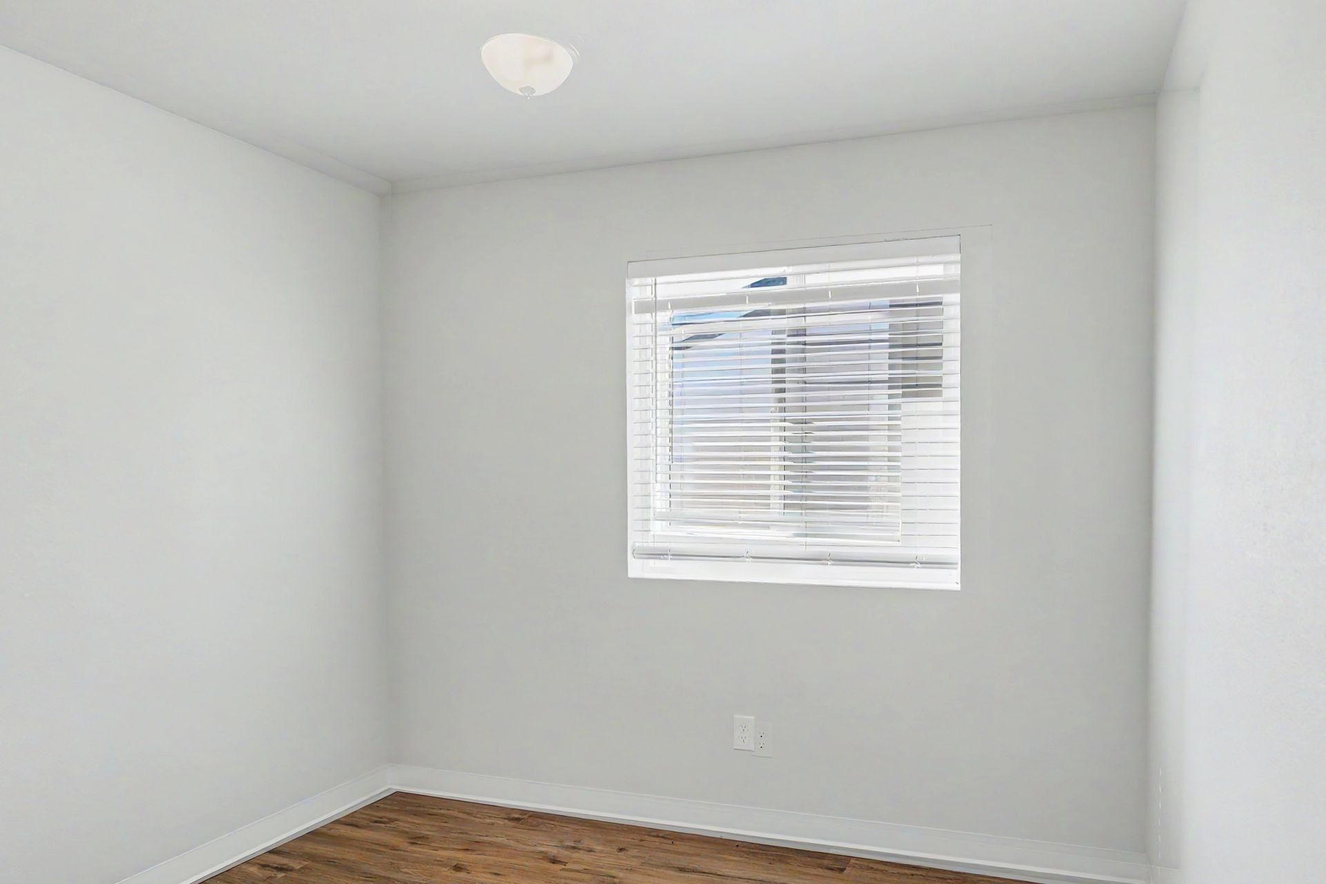 Empty white room with a window and wood floor