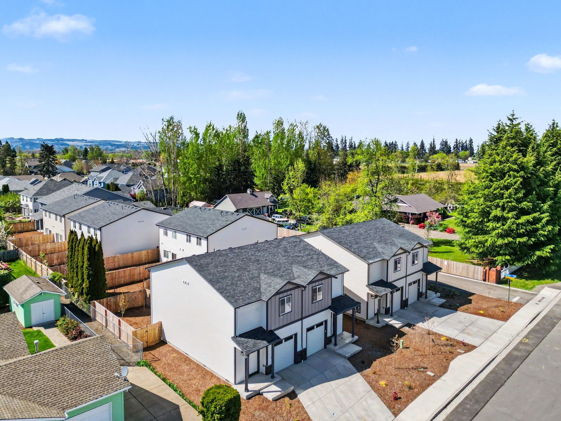 New suburban homes with gray roofs and white siding under a clear blue sky