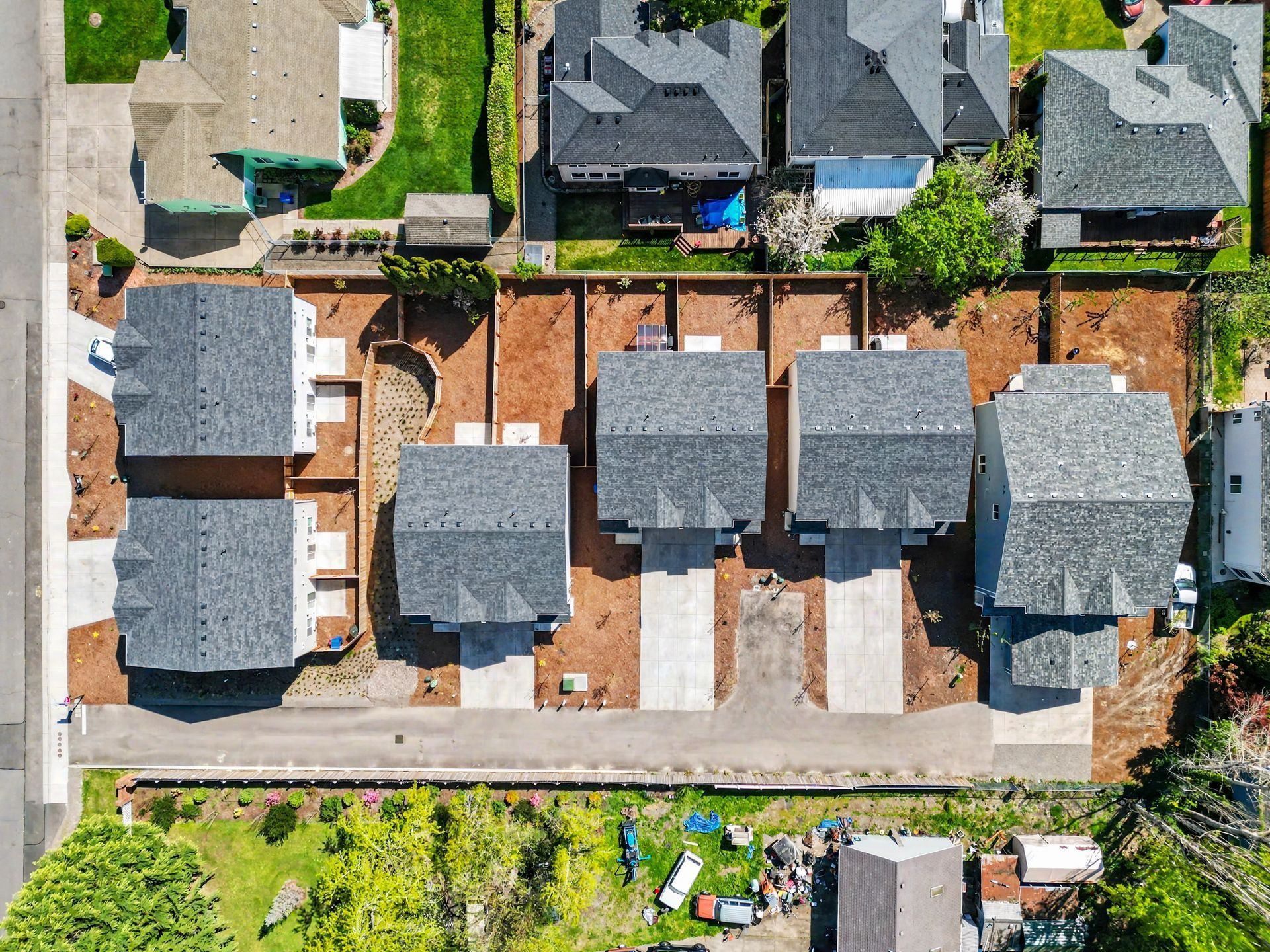 Aerial view of a suburban neighborhood with several houses, driveways, and backyards.