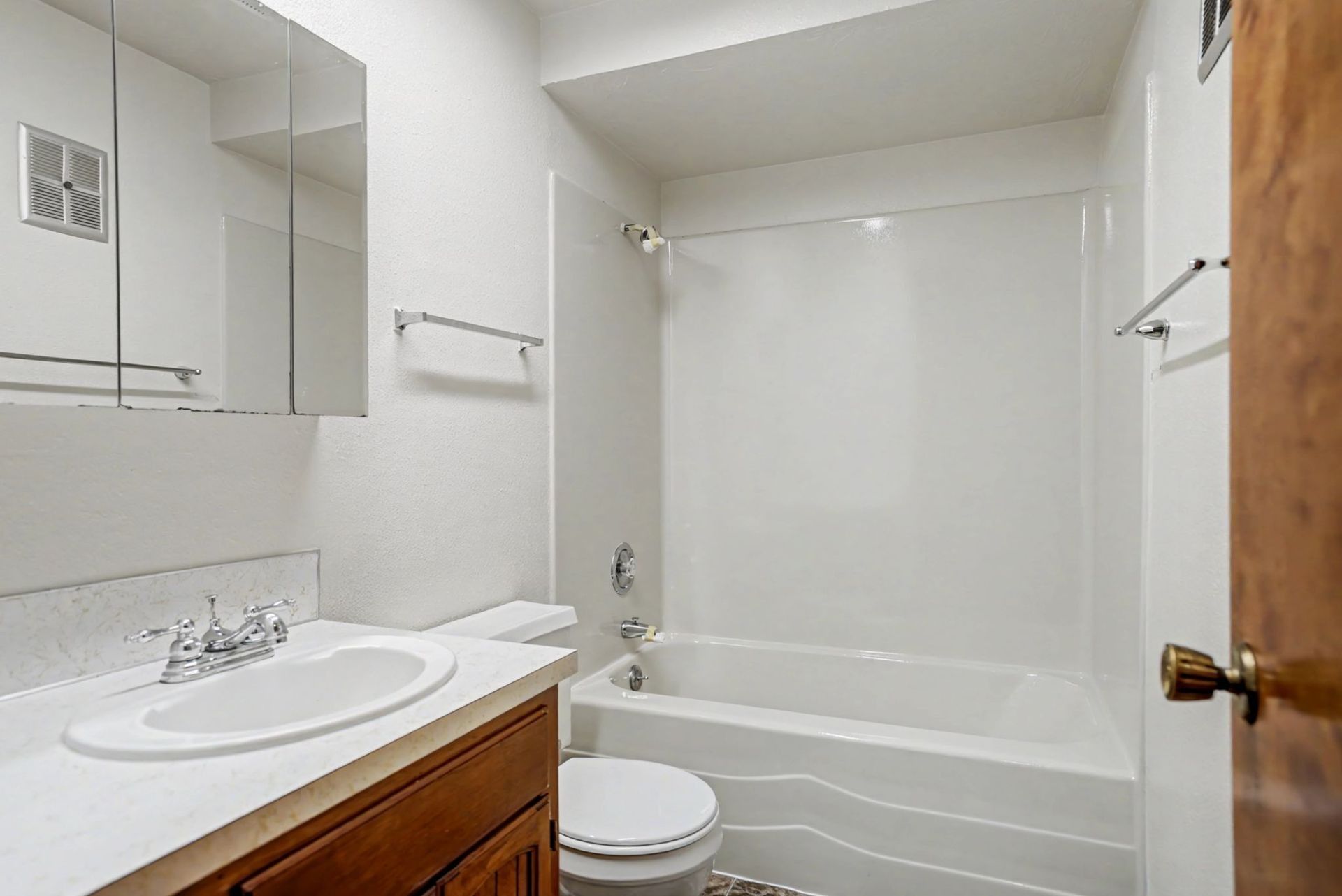White bathroom with vanity, toilet, bathtub, and mirror cabinet