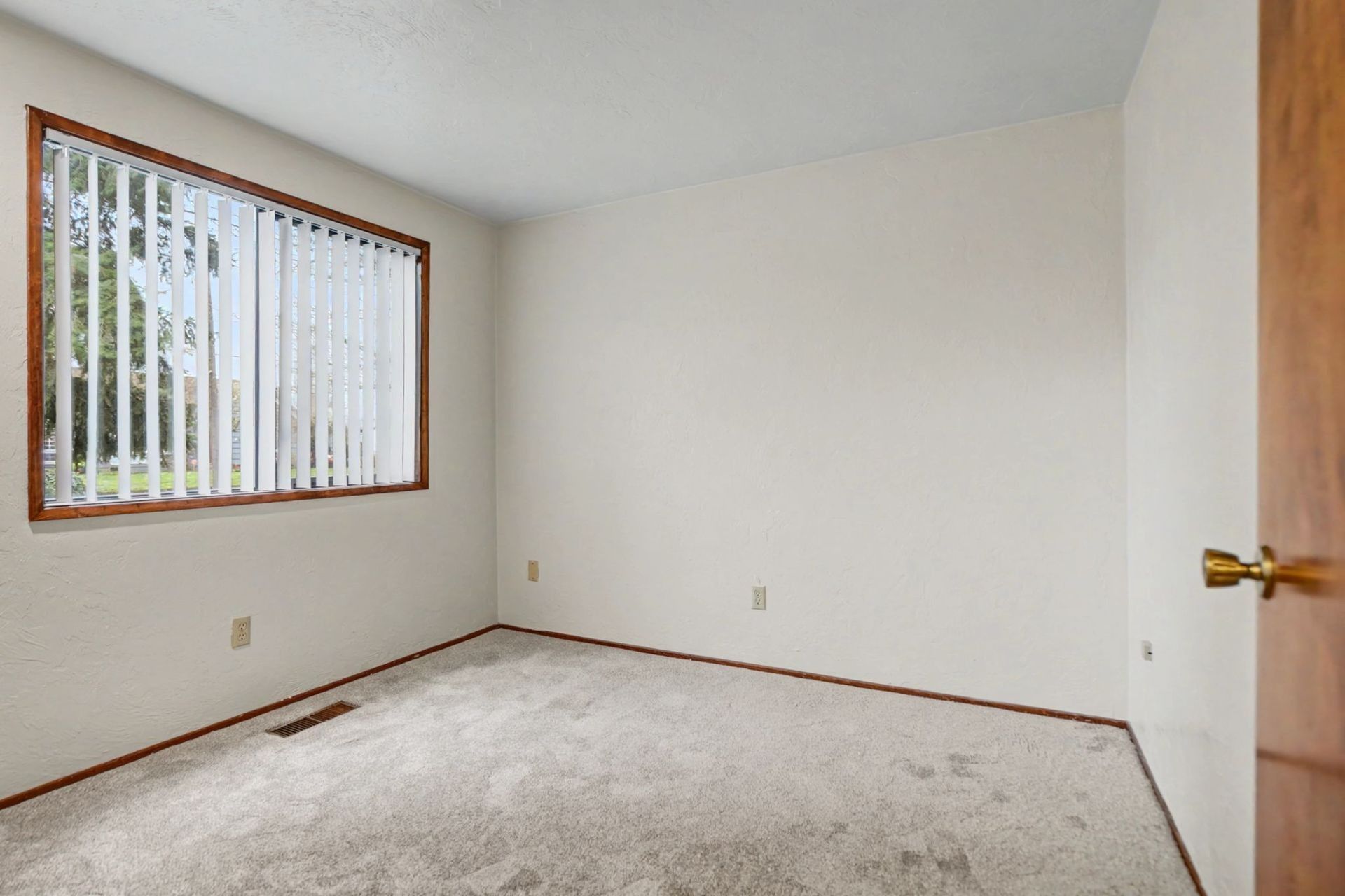 Empty beige bedroom with window blinds, white carpet, and wood trim