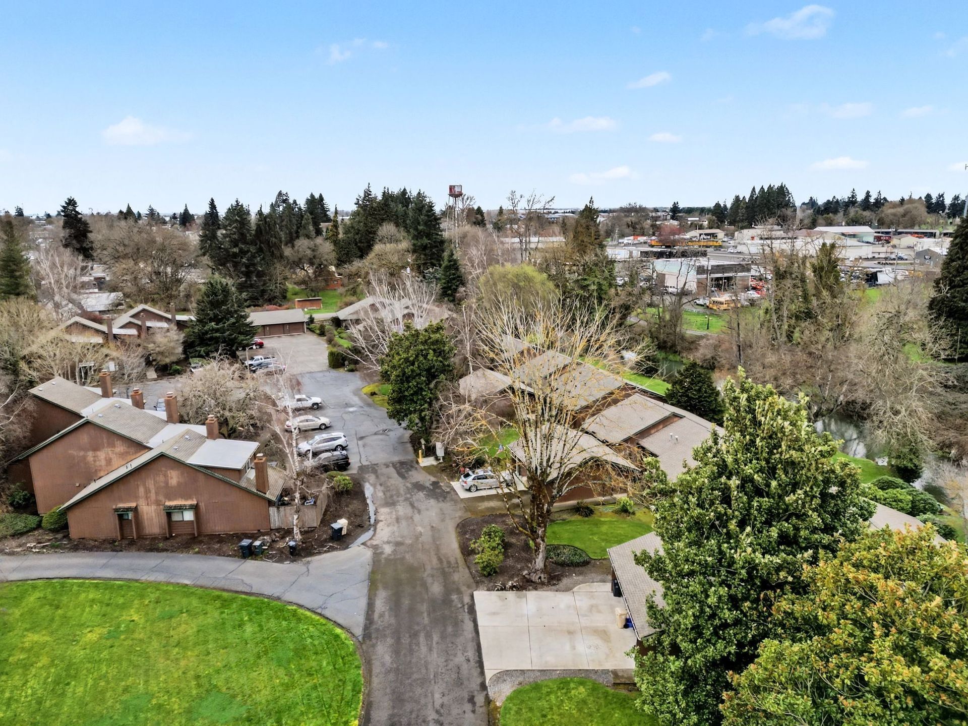 Suburban neighborhood with houses, trees, and a paved road under a clear blue sky