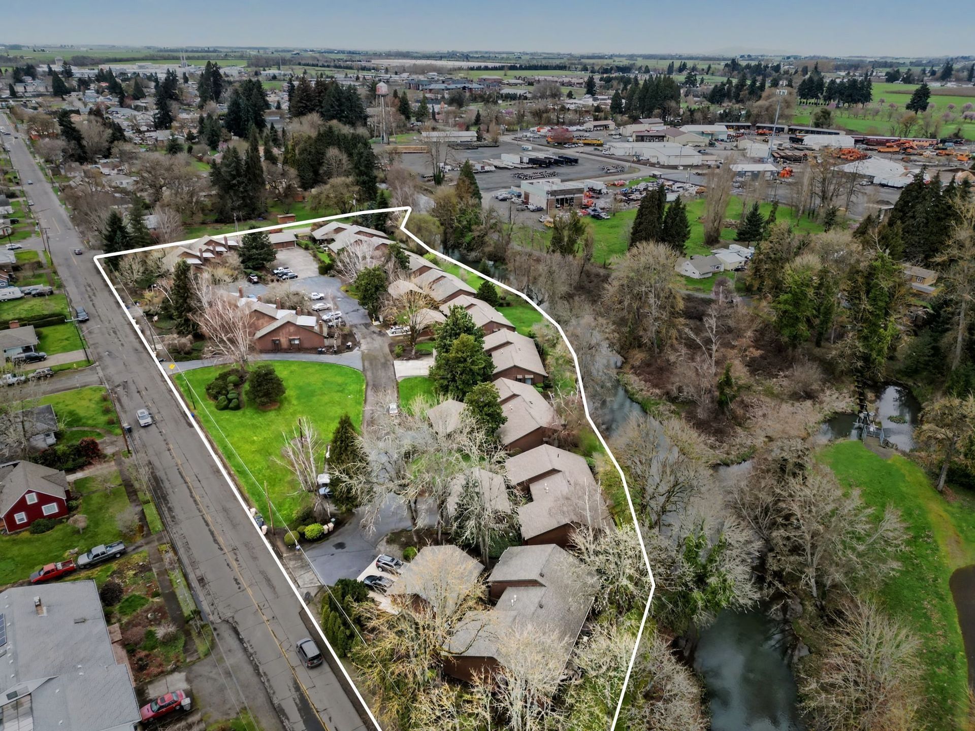 Aerial view of a suburban neighborhood with homes, roads, trees, and open green space