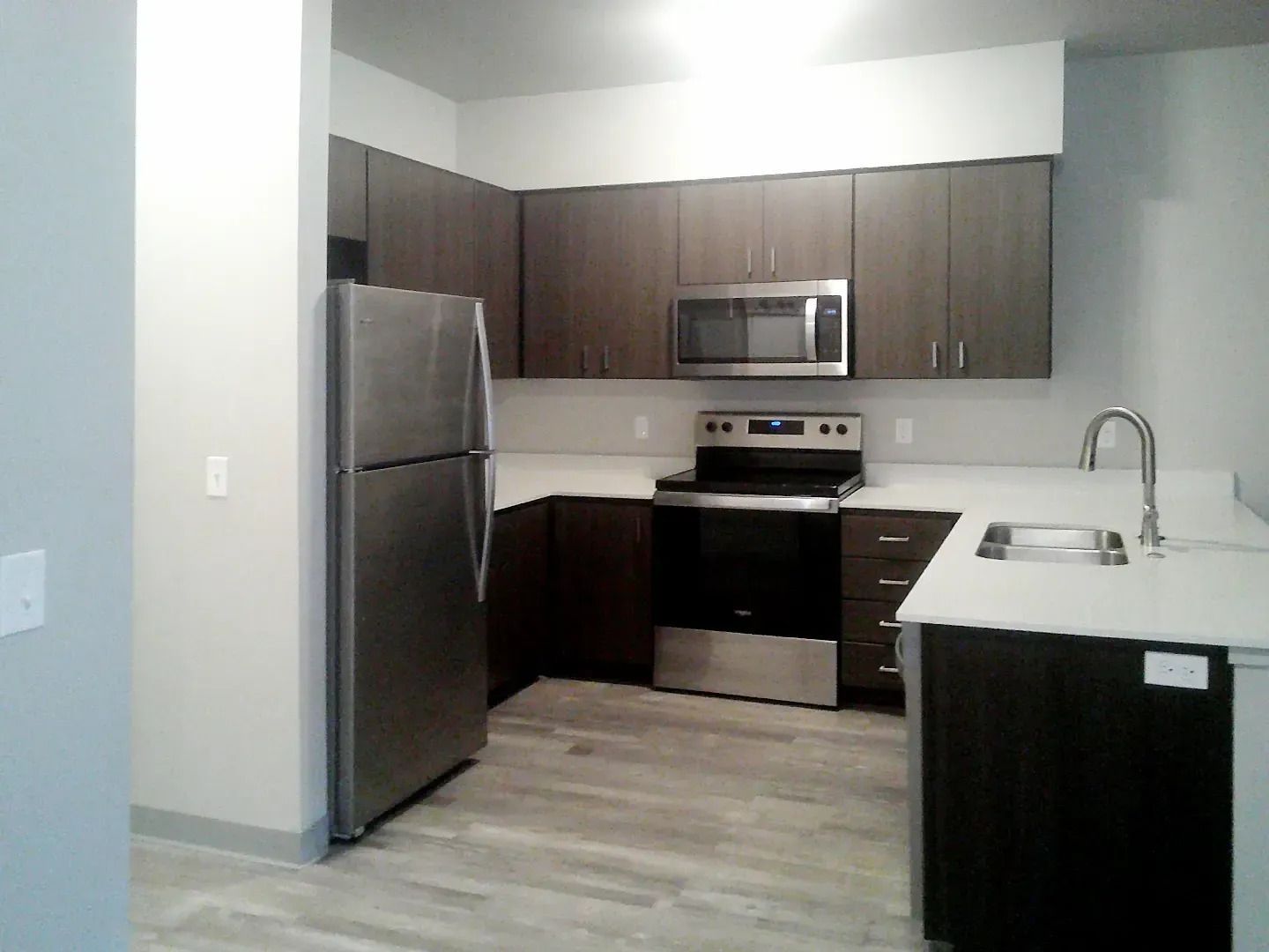 Modern kitchen with stainless steel appliances, dark cabinets, and a white countertop island