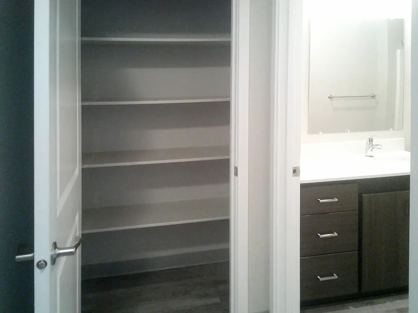 Empty gray closet beside a bathroom vanity with sink and drawers