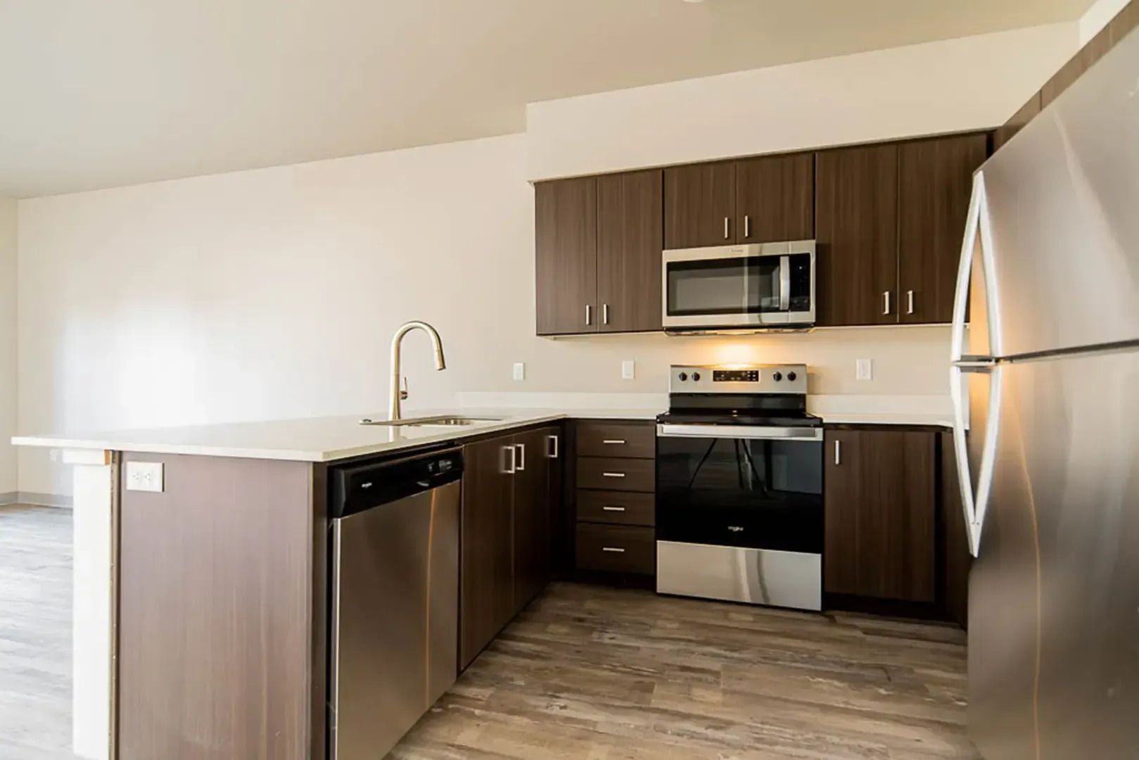 Modern kitchen with dark wood cabinets, stainless steel appliances, and a white island counter