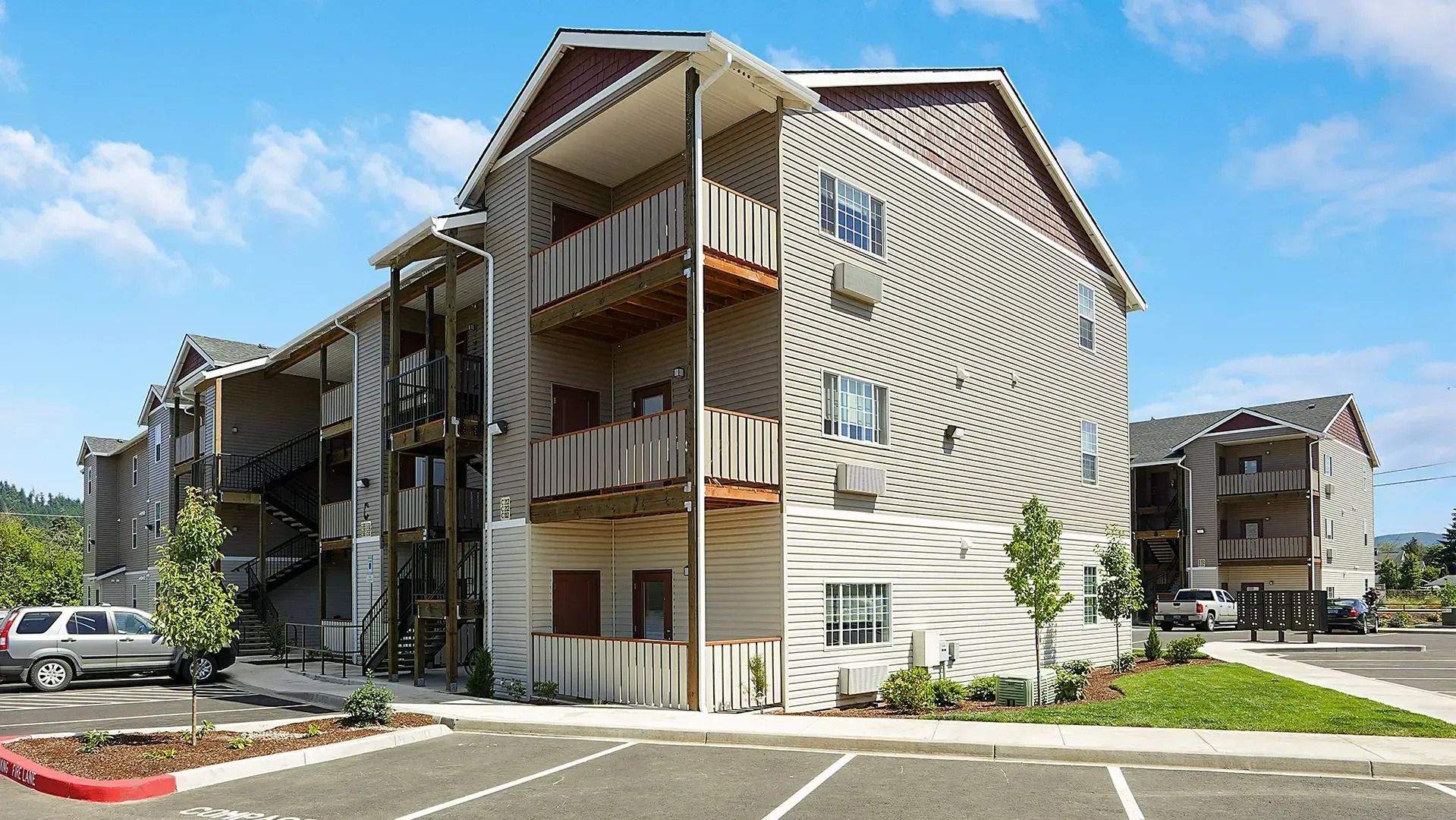 Apartment building with balconies and parked cars on a sunny day