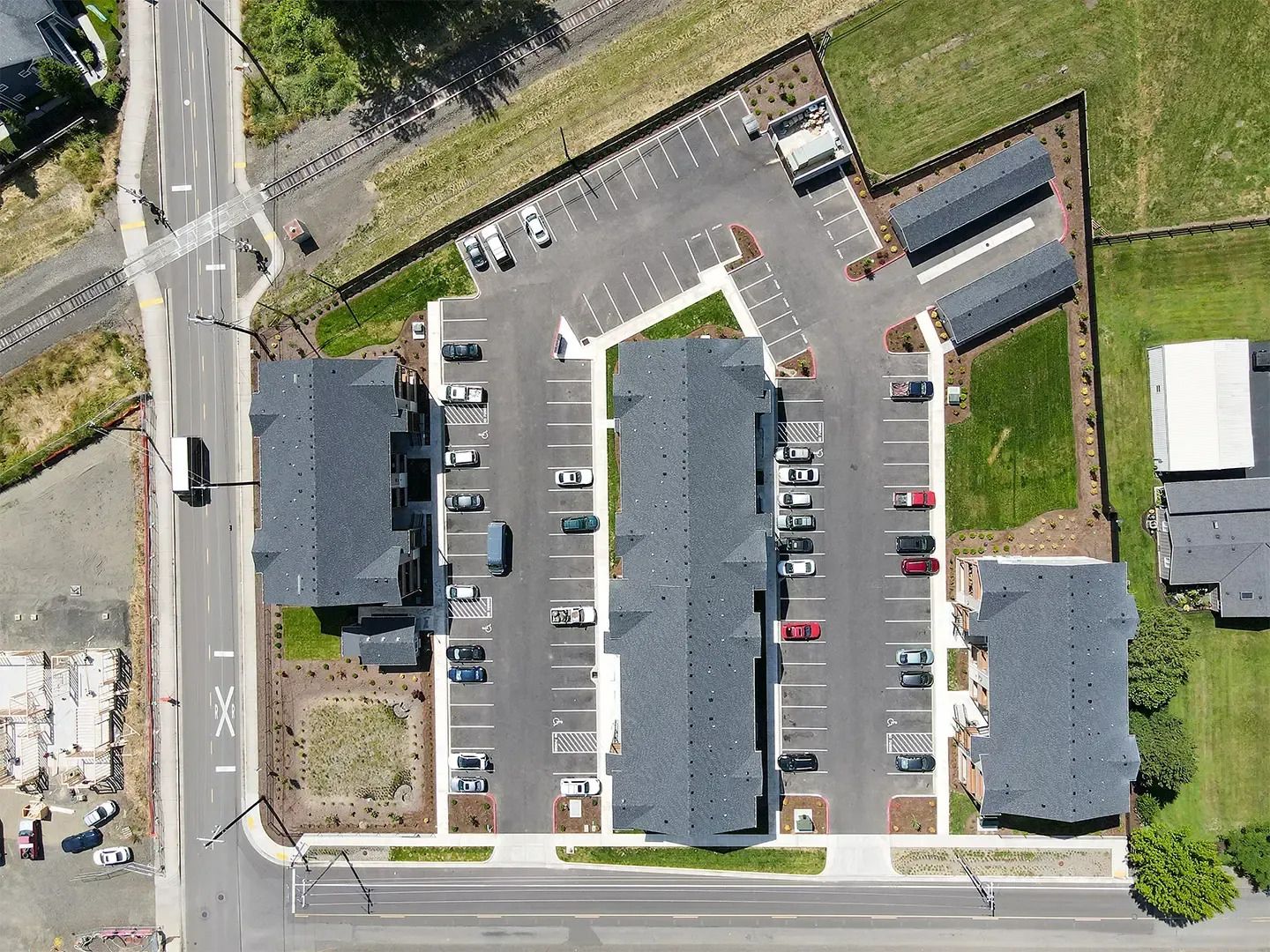 Aerial view of an apartment complex with parking lots, roads, and grassy areas nearby.