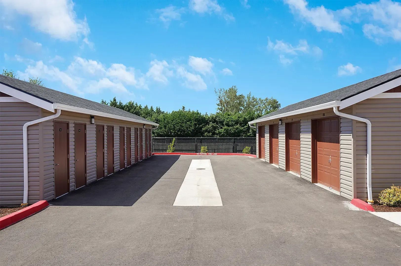 Driveway between two rows of storage units under a blue sky