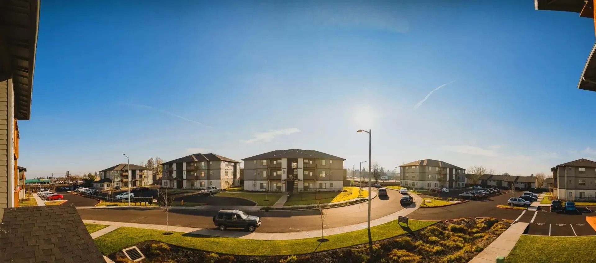 Panoramic view of a modern apartment complex and roundabout under a clear blue sky