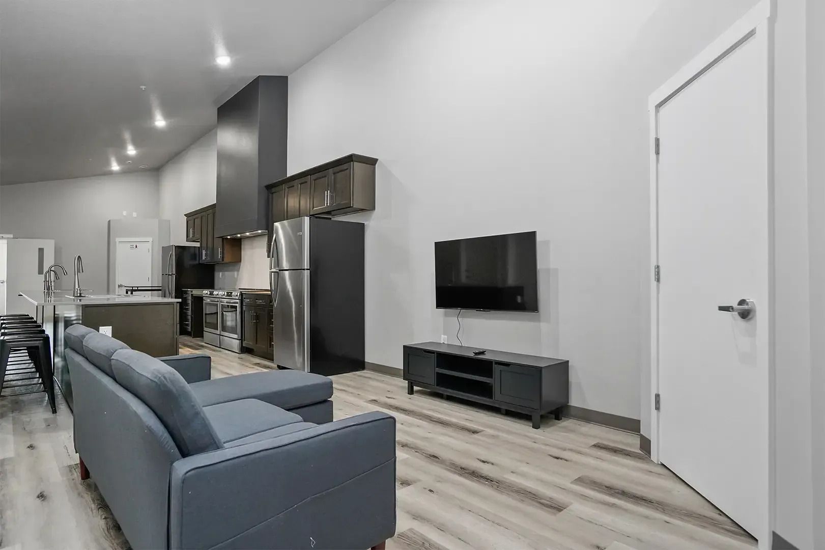 Modern open-plan living room with blue sofa, TV, and kitchen in the background