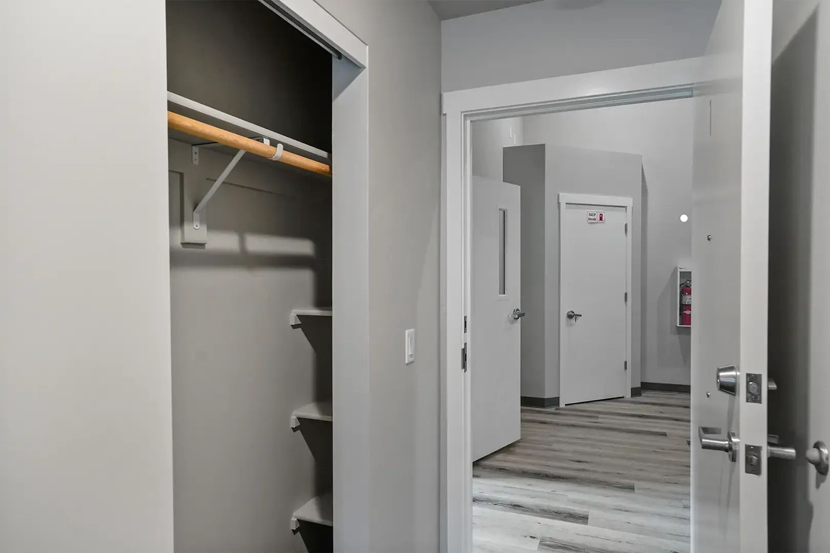 Open closet and hallway view in a modern apartment with white walls and wood flooring