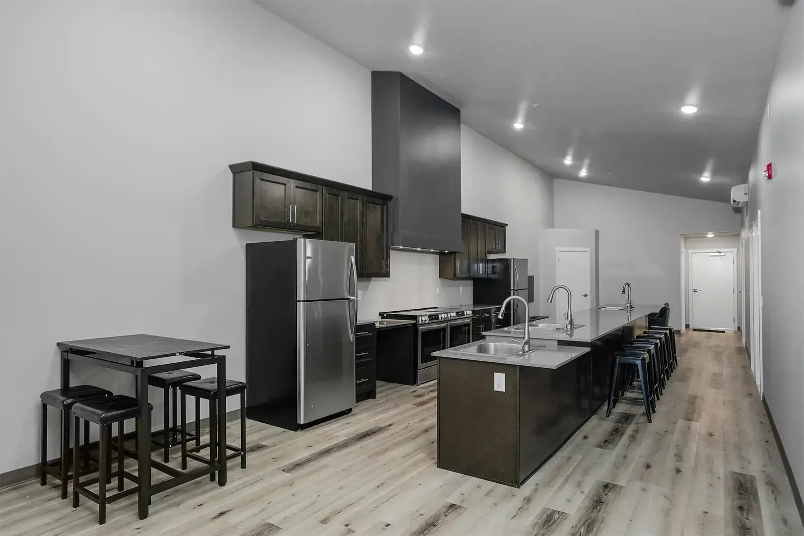 Modern open-concept kitchen with dark cabinets, stainless appliances, island, and adjacent dining table