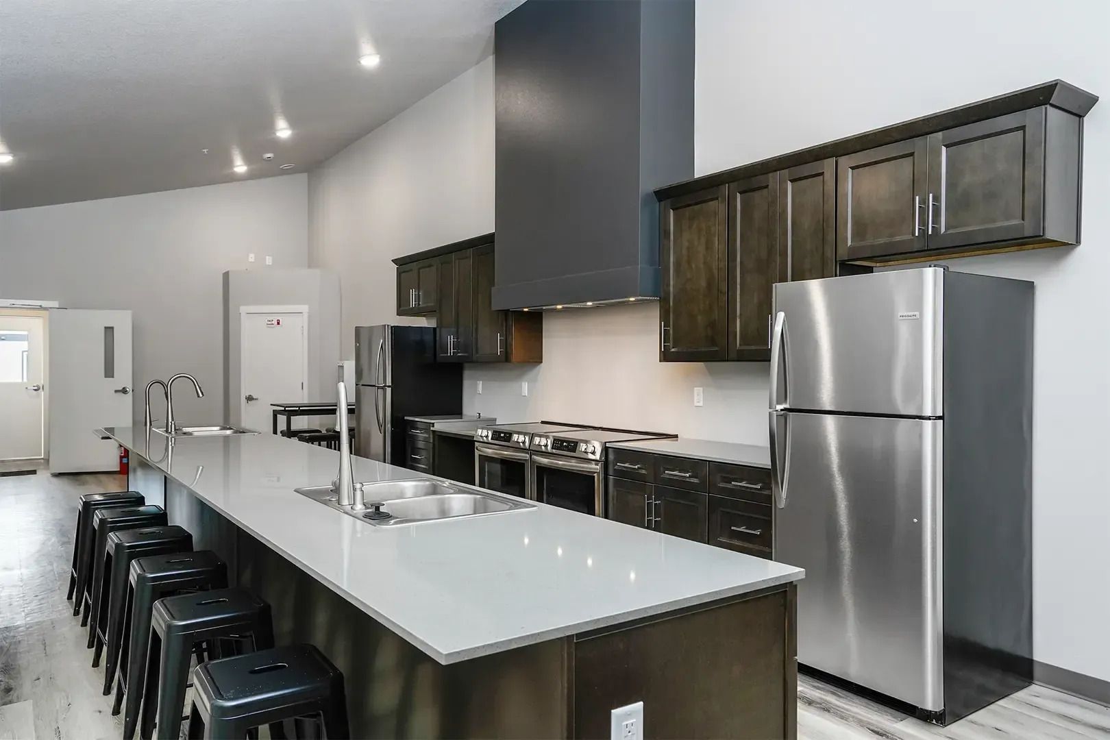 Modern kitchen with stainless appliances, dark cabinets, and a long island with black stools