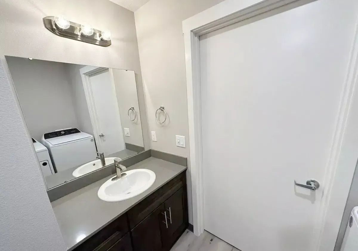 Small bathroom vanity with mirror, sink, dark cabinet, and white door.