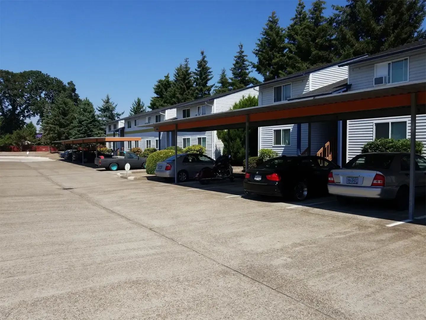 Apartment parking lot with covered carports and parked cars on a sunny day