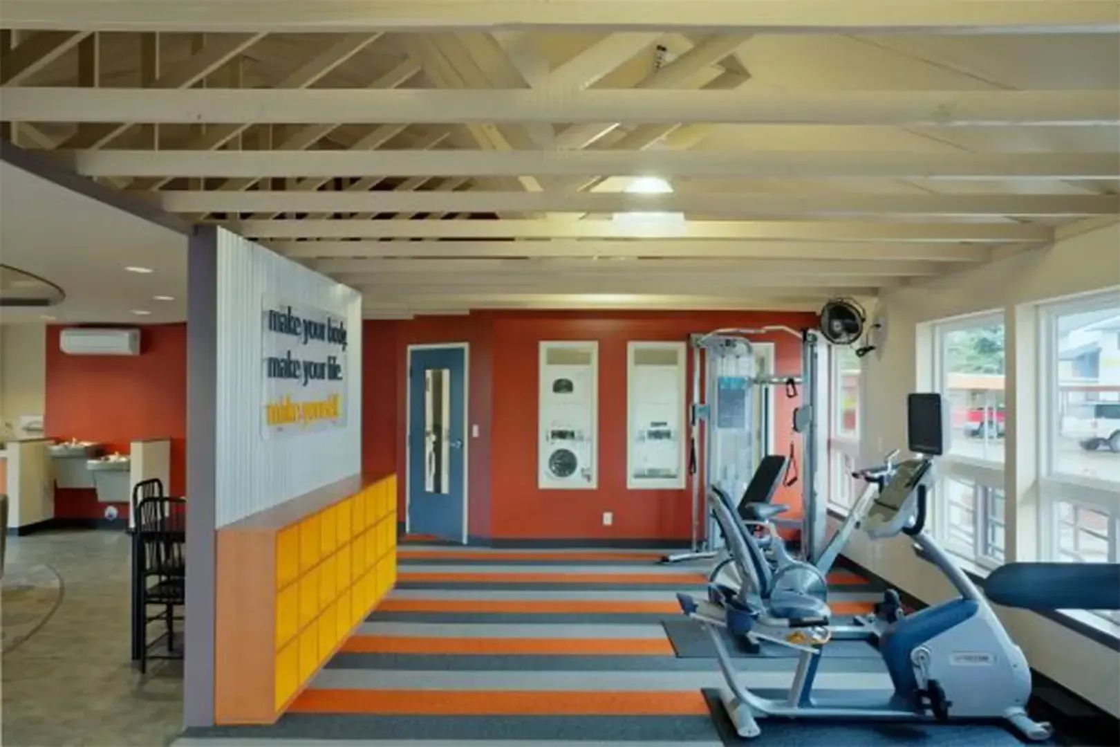 Modern gym interior with exercise bikes, orange-striped floor, and red wall accents