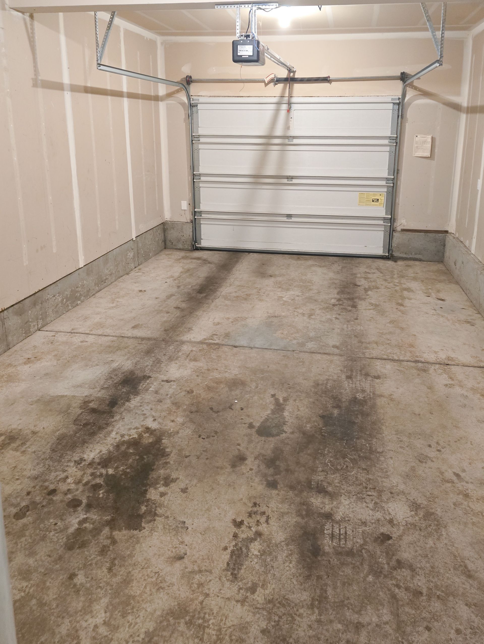 Empty two-car garage with white roll-up door and concrete floor.