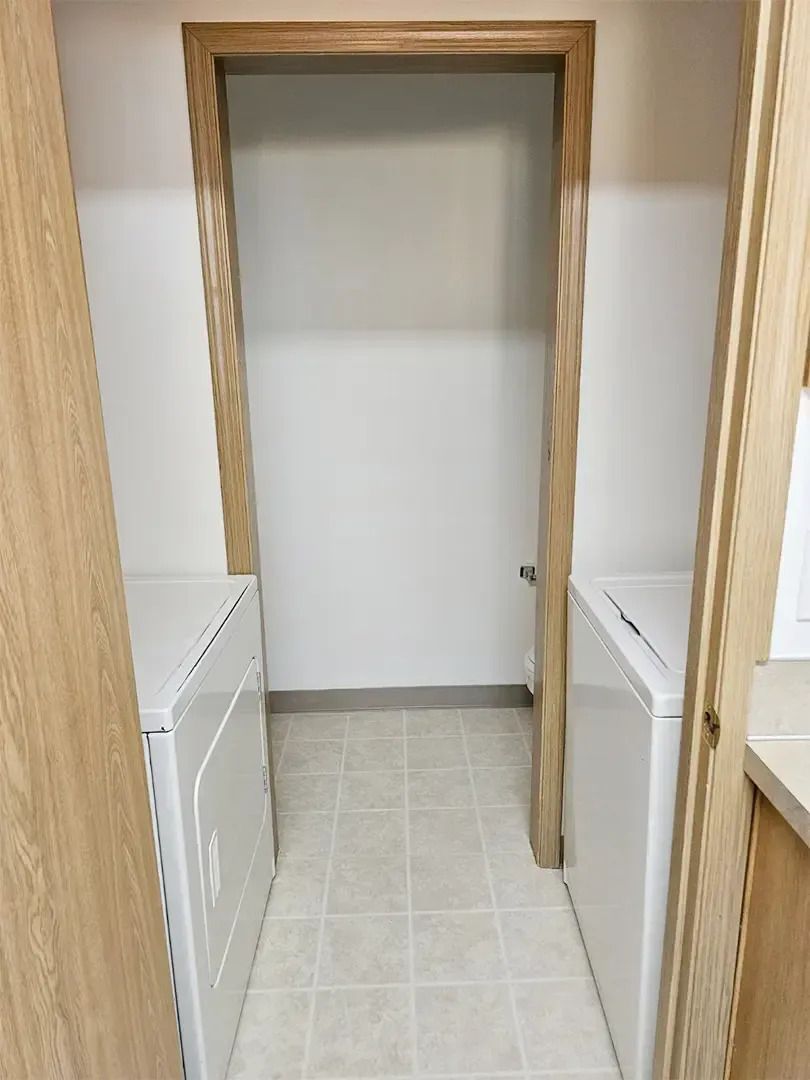 Empty closet with wooden doorframe, white shelves on both sides, and tiled floor.
