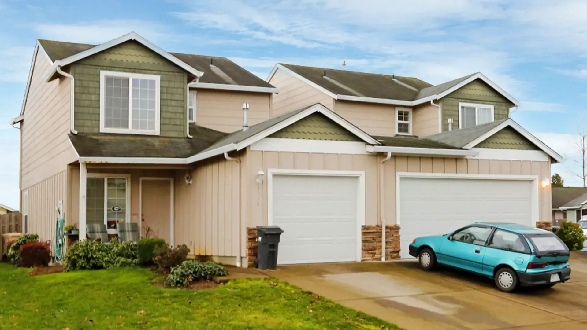 Suburban townhouse with a white garage and turquoise car parked in the driveway.