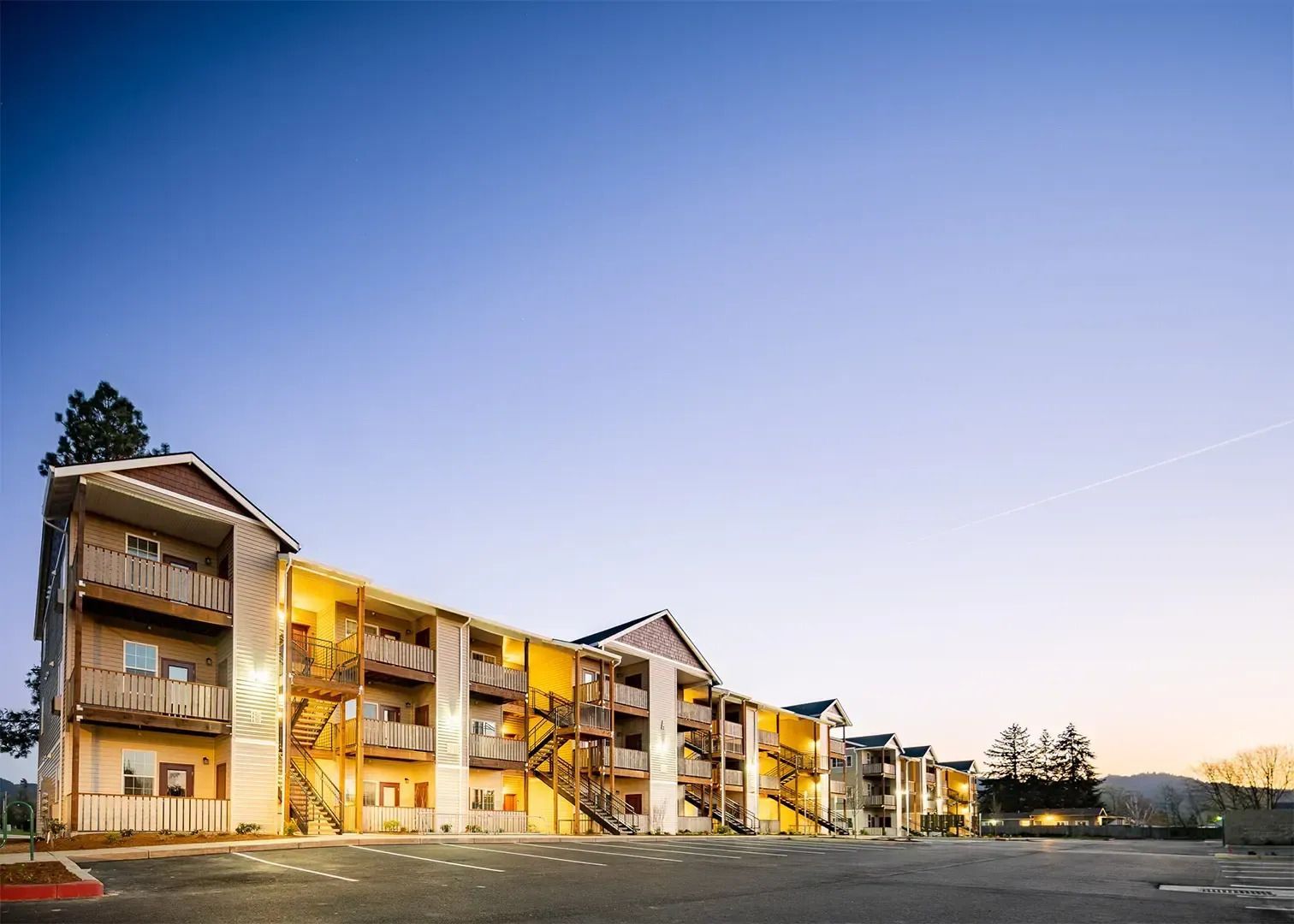 Modern apartment buildings at dusk with warm lights and a clear sky