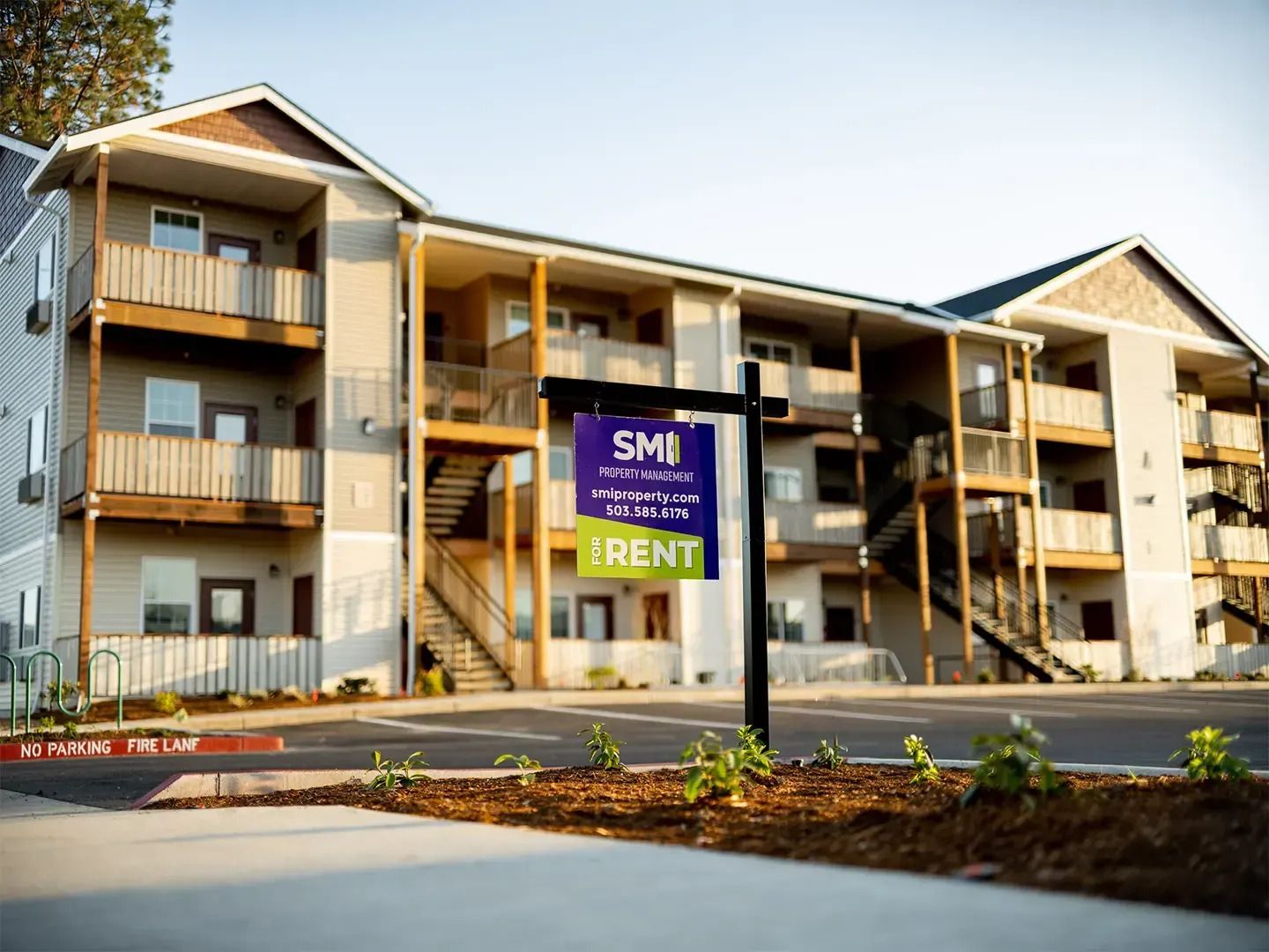 Modern apartment building with balconies and a large “SOLD/RENT” sign out front