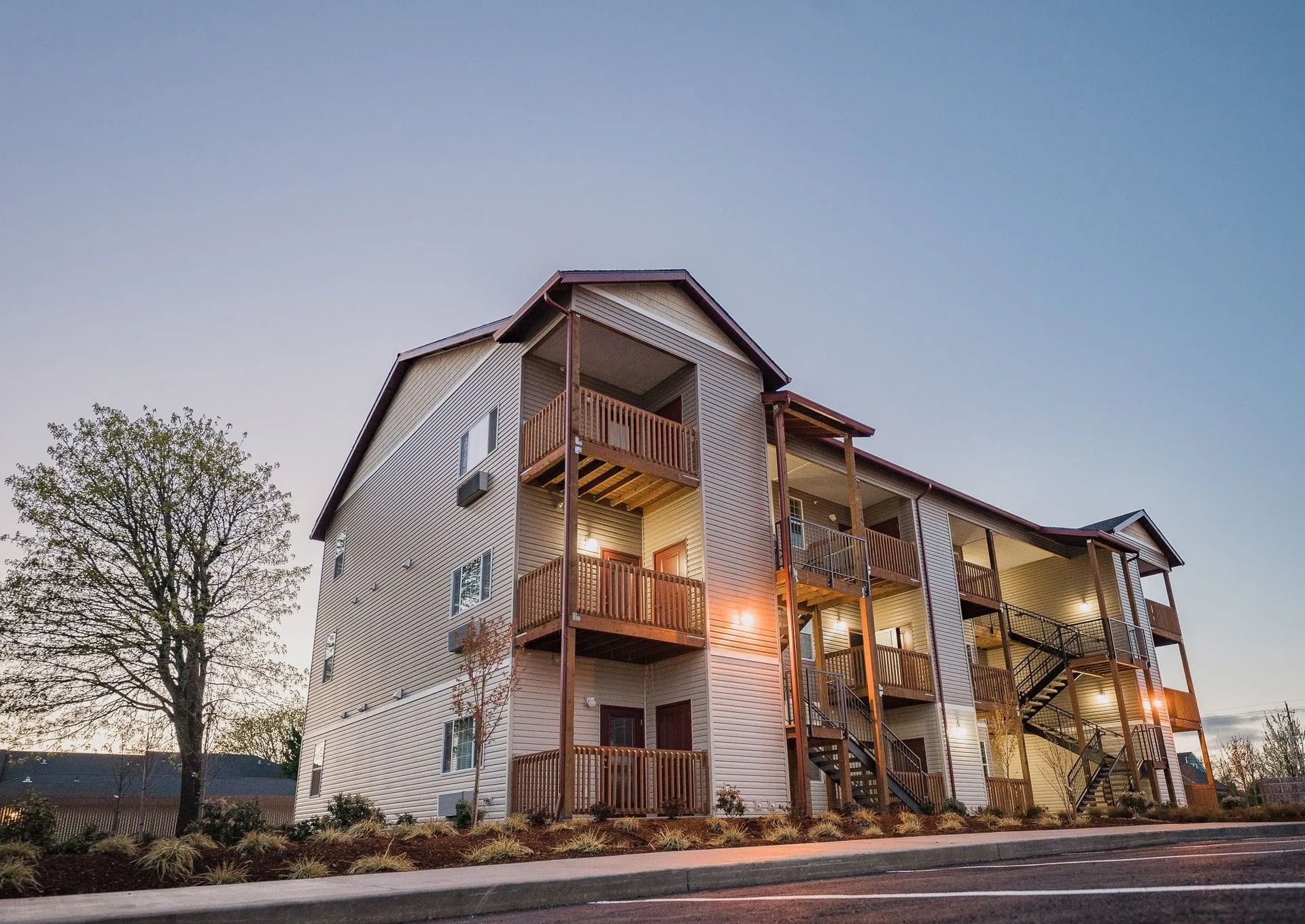 Modern apartment building at dusk with warm lights and landscaped grounds