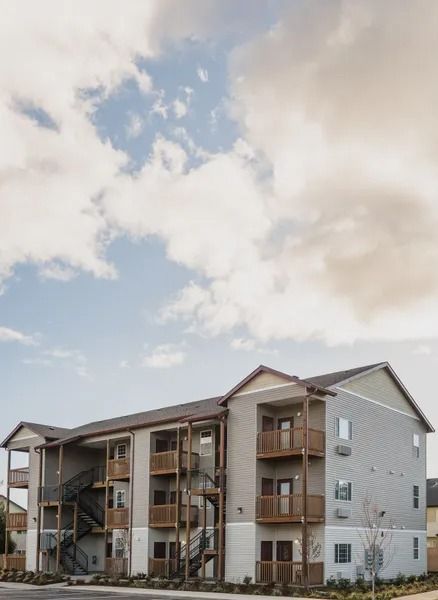 Three-story apartment building with balconies under a cloudy sky
