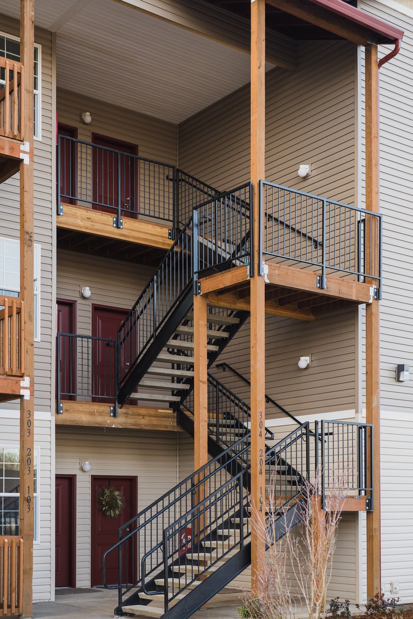 Exterior view of apartment balconies and black metal staircases on a tan building