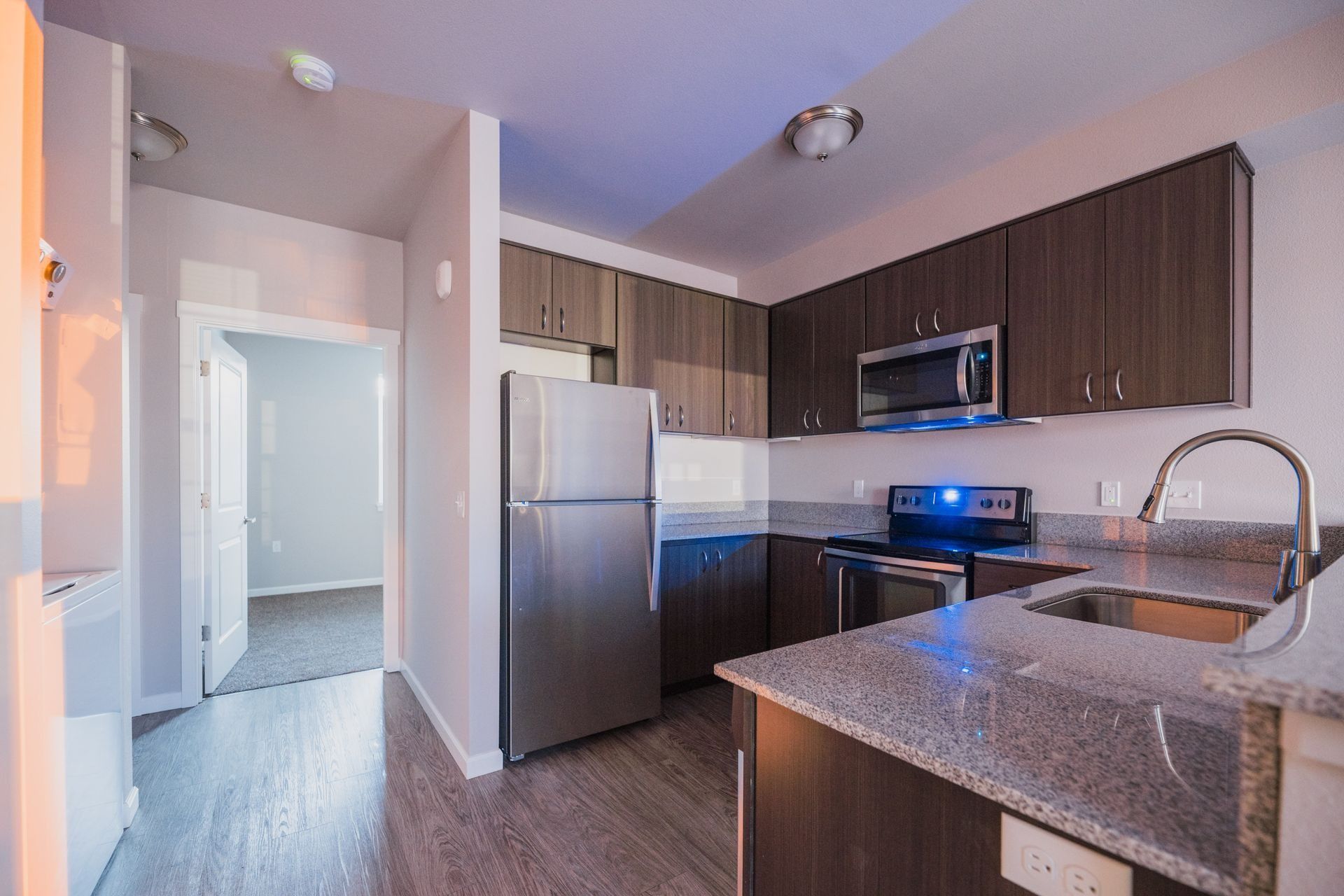 Modern kitchen with stainless steel appliances, dark cabinets, and a granite island countertop