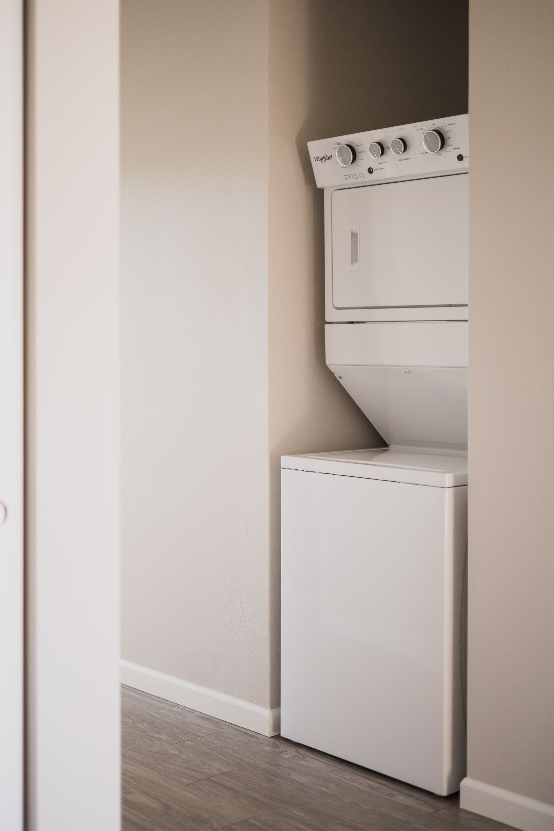 Stacked white washer and dryer in a narrow closet alcove