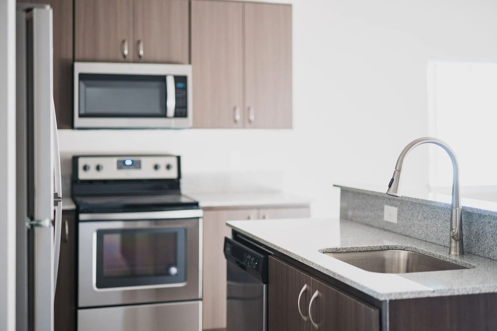 Modern kitchen with stainless steel appliances, wood cabinets, and a sink on a dark countertop
