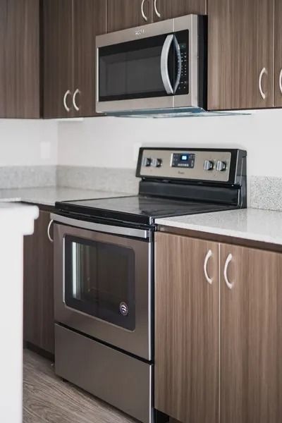 Modern kitchen with stainless steel stove, microwave, and wood cabinets.