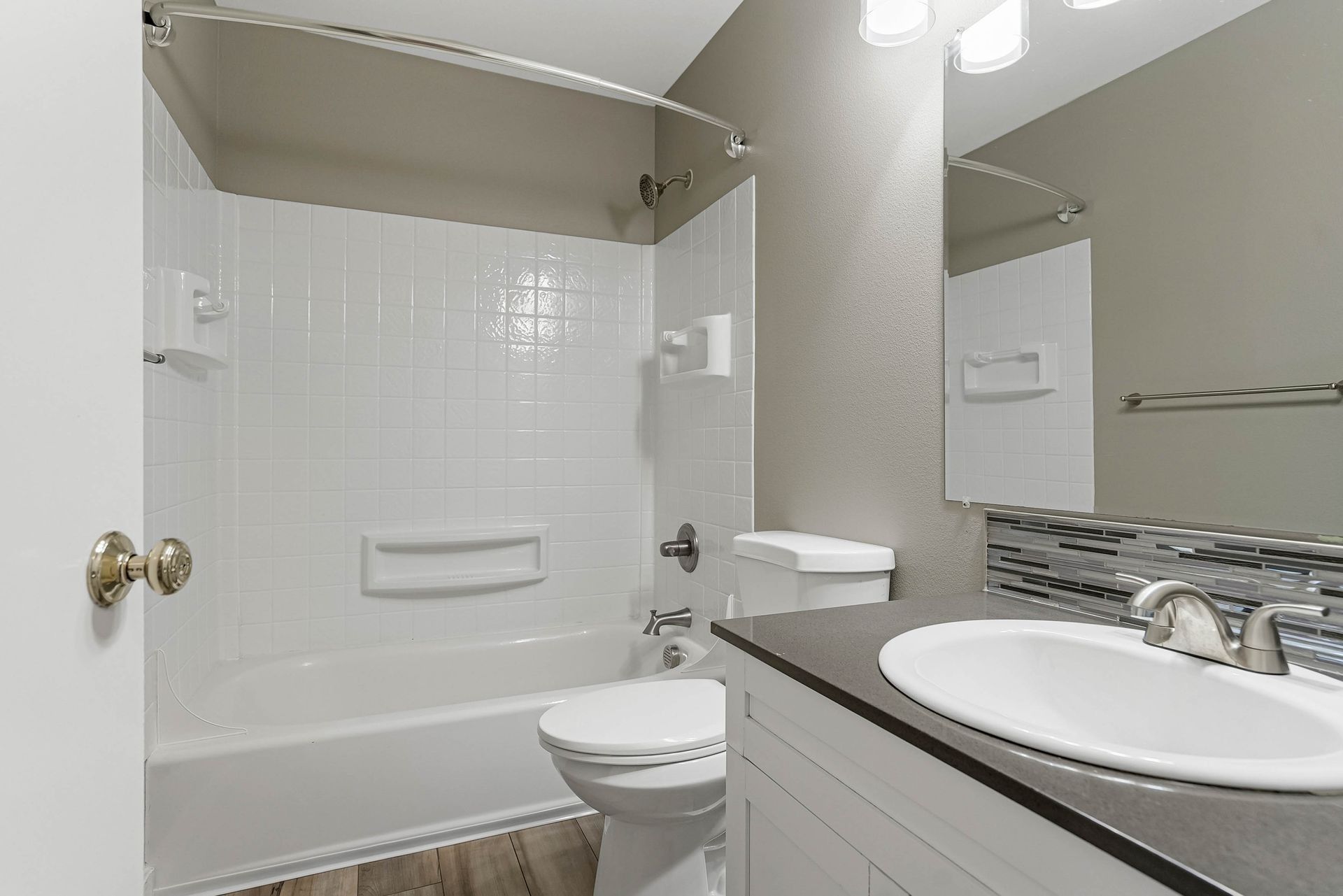 Small bathroom with a tub-shower, toilet, sink vanity, and mirror with gray and white finishes