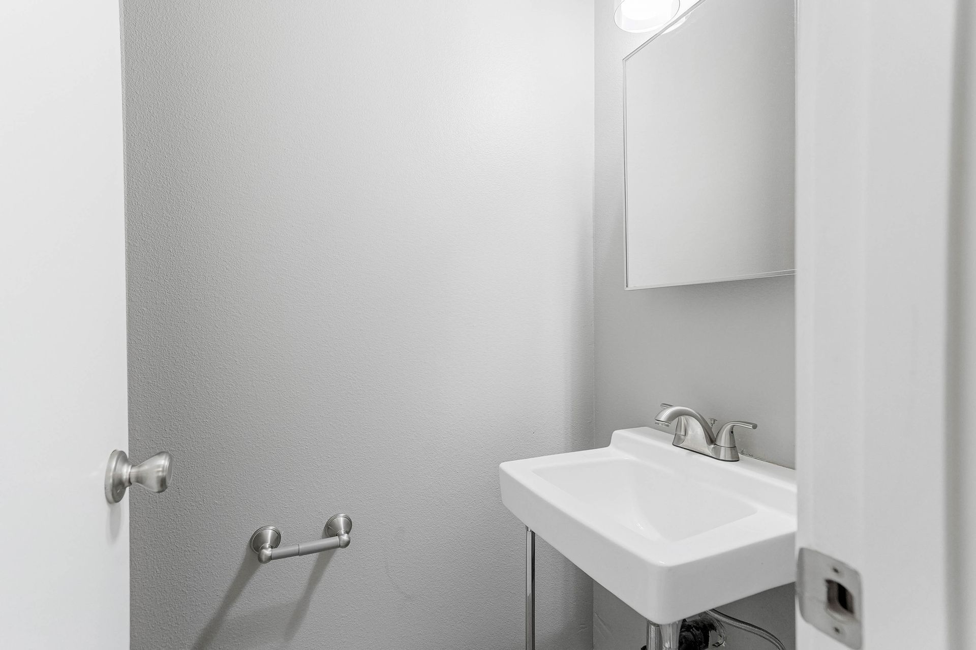 Small bathroom with frosted shower door and white sink, toilet partially visible.