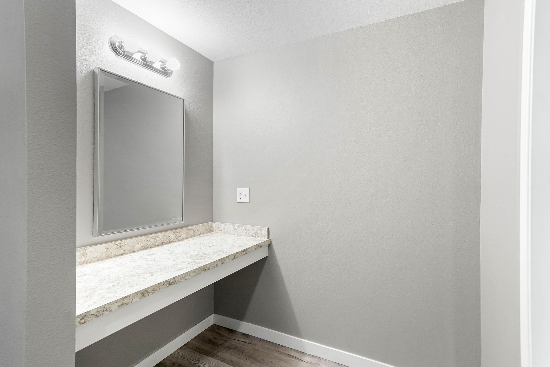 Modern vanity area with large mirror, white countertop, and gray walls in a bright room
