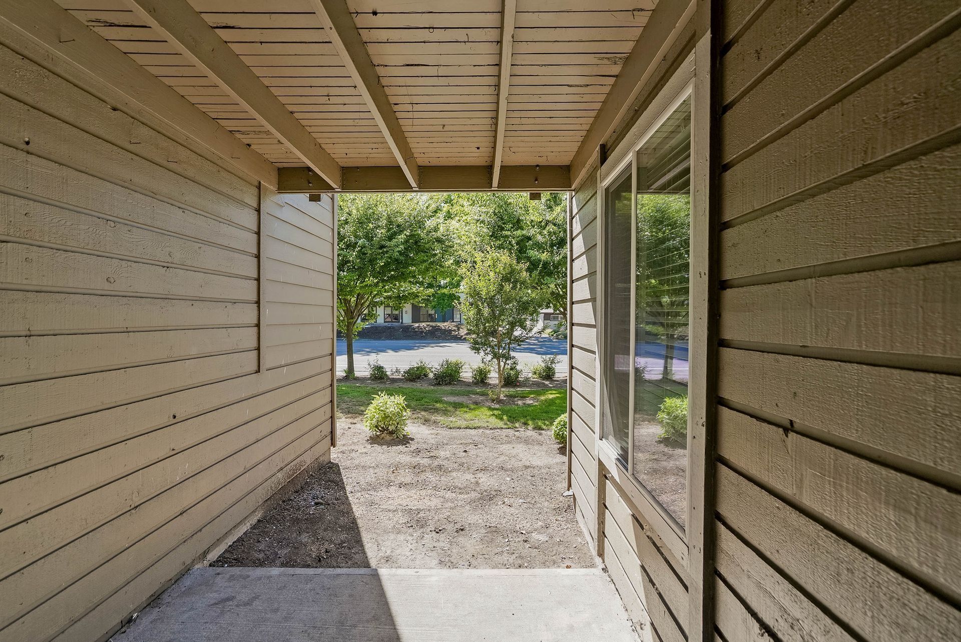 Covered apartment walkway opening to a sunny courtyard and street beyond