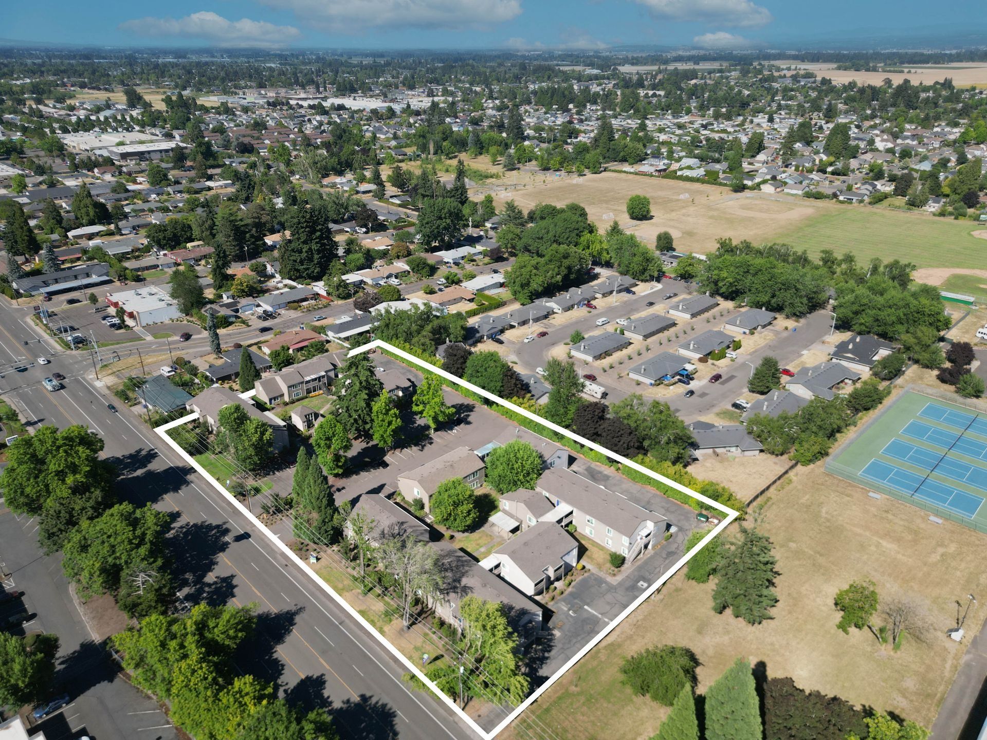 Aerial view of suburban neighborhood with homes, streets, parkland, and tennis courts